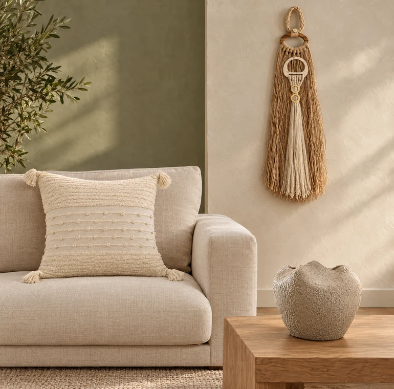Sala com almofada crua, vaso de cerâmica e colar de parede da ANNI Home